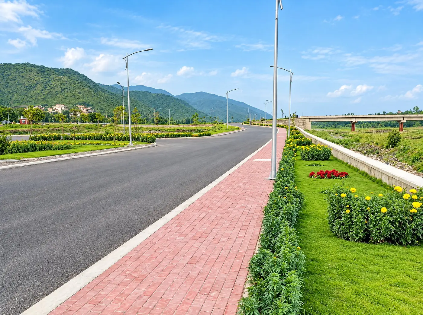 Brick footpath with marigold beds, the bridge over the river and the hills behind